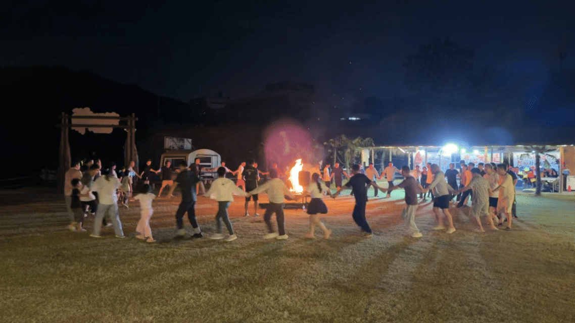 Shanghai Duomu employees gathering around a campfire during the evening in Anji