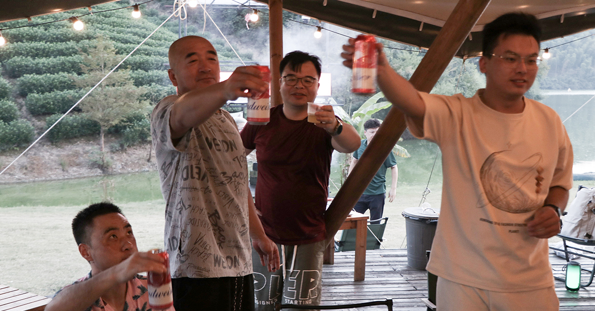Shanghai Duomu employees gathering around a campfire during the evening in Anji